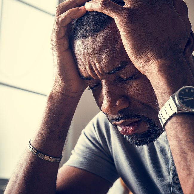 man suffering with anxiety with head in hands