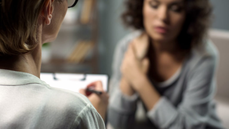 female counsellor with clipboard talking to woman