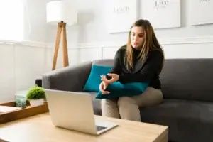 A woman comfortably seated on a couch, participating in an online therapy session.